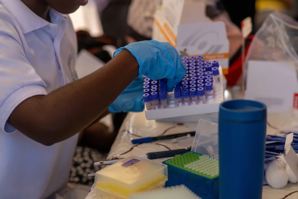 Laboratory worker in gloves organizing test tubes.