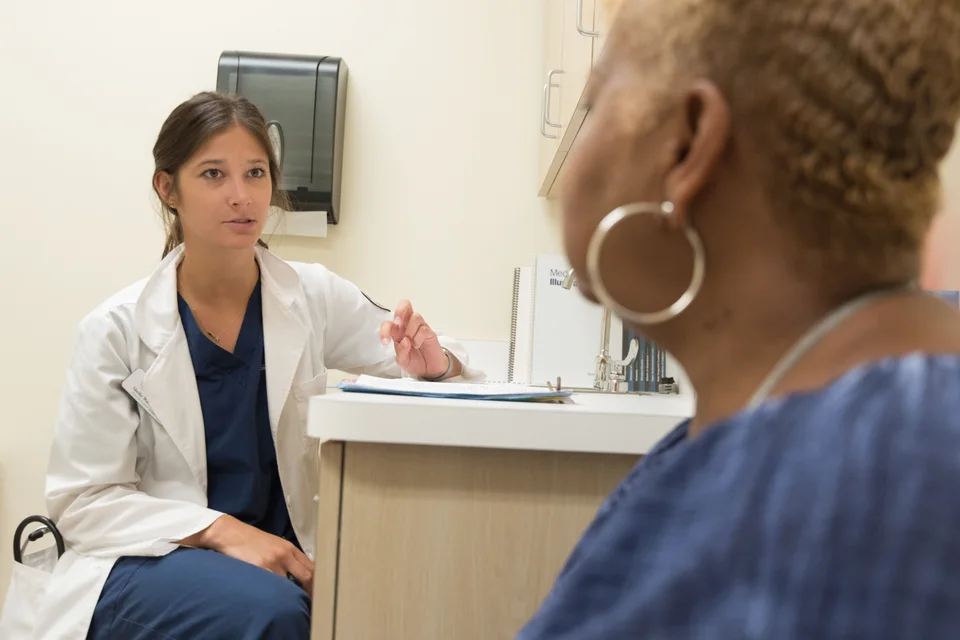 Clinician speaking with a woman during a medical consultation.